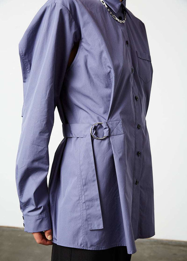 INTERNATIONAL CITIZEN.  Style: Artist Shirt. Close up side front view. Style has an oversized shirt with a pen pocket at the chest, open underarms for breathability, and back belt ties that adjust at the front with silver rings. The shirt are made of Italian organic Cotton in Dreamstate Purple. Spiritually Infused, Sustainable Luxury Fashion in Berlin.
