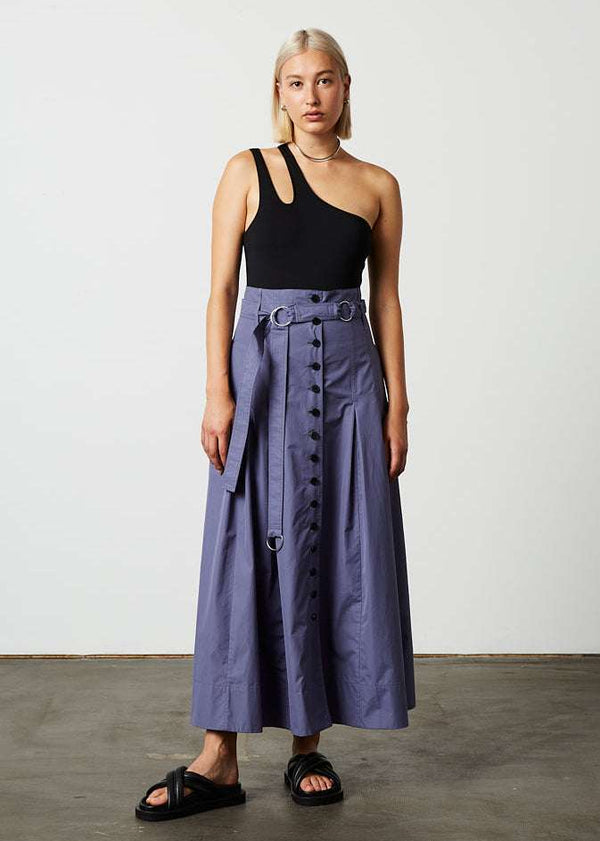 INTERNATIONAL CITIZEN.  Style: Button Skirt. Front full body view. A Button Skirt with box pleats below the hips. Detachable belt with silver ring details for closure. The skirt is made of Italian organic Cotton in Dreamstate Purple. Spiritually Infused, Sustainable Luxury Fashion in Berlin.