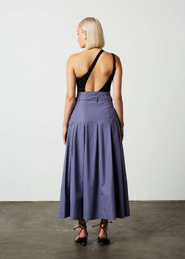 INTERNATIONAL CITIZEN.  Style: Button Skirt. Back full body photo. A Button Skirt with box pleats below the hips. The skirt is made of Italian organic Cotton in Dreamstate Purple. Spiritually Infused, Sustainable Luxury Fashion in Berlin.