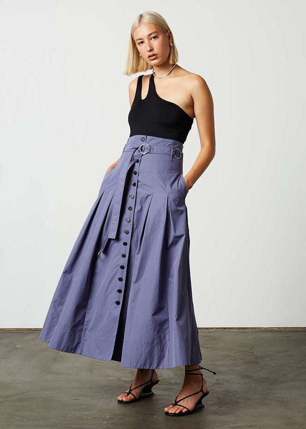 INTERNATIONAL CITIZEN.  Style: Button Skirt. Front movement photo. A Button Skirt with box pleats below the hips. The skirt is made of Italian organic Cotton in Dreamstate Purple. Spiritually Infused, Sustainable Luxury Fashion in Berlin.