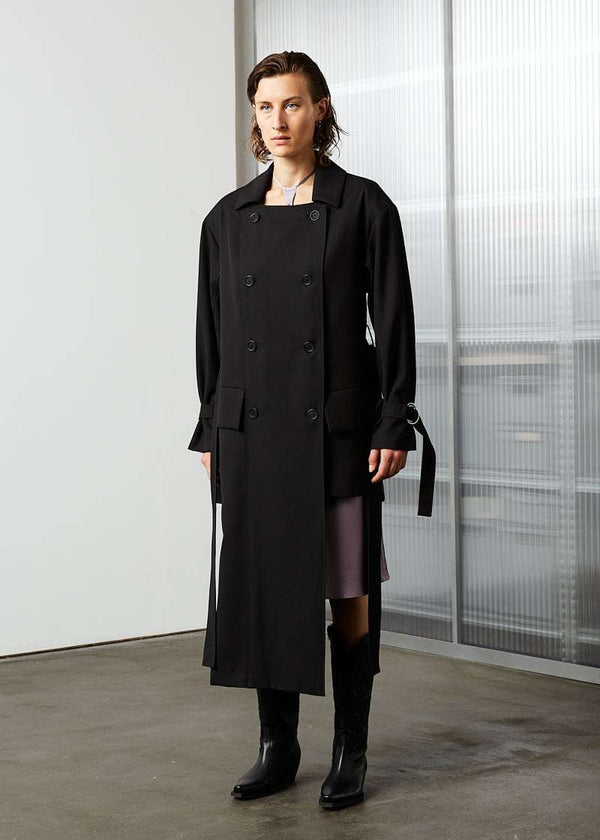 INTERNATIONAL CITIZEN.  Style: The Eclipse Jacket. A unisex, asymmetrical along the hemline and oversized with soft shoulder pads for collapsed structure. Front view un belted.  Made of Italian RWS Wool, Obsidian Black. Spiritually Infused, Sustainable Luxury Fashion in Berlin.