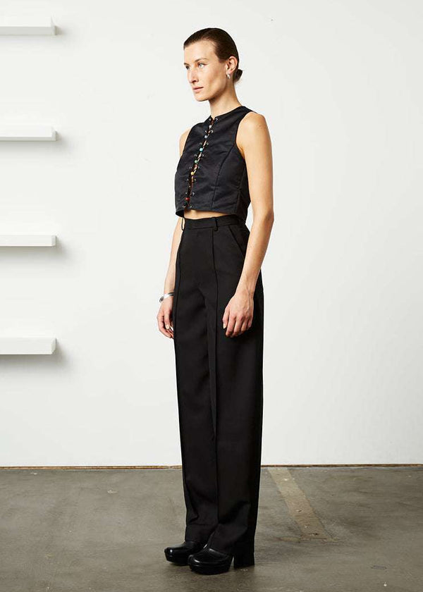 INTERNATIONAL CITIZEN.  Style: The Ribcage Trouser is a high waisted pant, with a perfectly tapered pin-tuck leg that falls over the shoe. Made of Italian Wool RWS, Obsidian Black. Spiritually Infused, Sustainable Luxury Fashion in Berlin. Side front view.