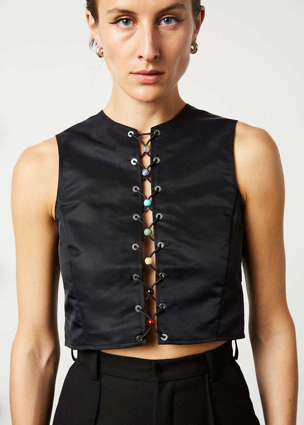 INTERNATIONAL CITIZEN.  Style: The Seven Chakra Top is an unlined shell top with an exposed silver metal zipper closure at the back. It features metal eyelets down the front and chakra crystals looped with a braided cord. Made of Italian post-consumer recycled Nylon, Obsidian Black. Spiritually Infused, Sustainable Luxury Fashion in Berlin. Front photo.