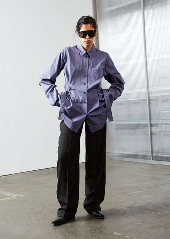 INTERNATIONAL CITIZEN.  Style: Artist Shirt. Full body front view. Style has an oversized shirt with a pen pocket at the chest, open underarms for breathability, and back belt ties that adjust at the front with silver rings. The shirt are made of Italian organic Cotton in Dreamstate Purple. Spiritually Infused, Sustainable Luxury Fashion in Berlin.
