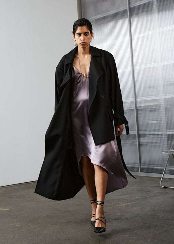 INTERNATIONAL CITIZEN.  Style: The Eclipse Jacket. A unisex, asymmetrical along the hemline and oversized with soft shoulder pads for collapsed structure. Model walking front view.  Made of Italian RWS Wool, Obsidian Black. Spiritually Infused, Sustainable Luxury Fashion in Berlin.