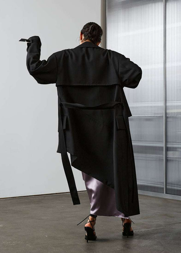 INTERNATIONAL CITIZEN.  Style: The Eclipse Jacket. A unisex, asymmetrical along the hemline. Model back view.  Made of Italian RWS Wool, Obsidian Black. Spiritually Infused, Sustainable Luxury Fashion in Berlin.