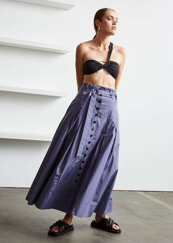 INTERNATIONAL CITIZEN.  Style: Button Skirt. Front movement photo. A Button Skirt with box pleats below the hips. Detachable belt with silver ring details for closure. The skirt is made of Italian organic Cotton in Dreamstate Purple. Spiritually Infused, Sustainable Luxury Fashion in Berlin.