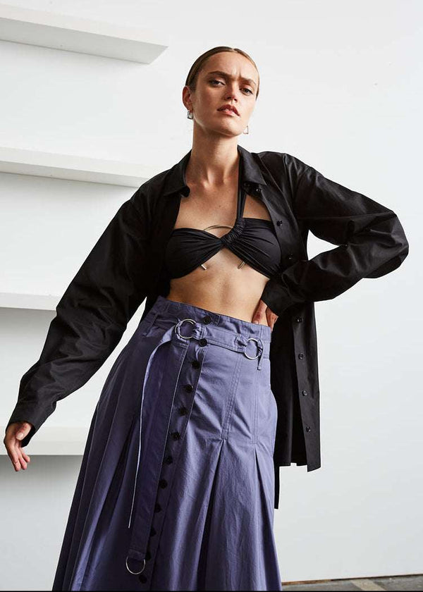 INTERNATIONAL CITIZEN.  Style: Button Skirt. Front close up photo with a shirt. A Button Skirt with box pleats below the hips. Detachable belt with silver ring details for closure. The skirt is made of Italian organic Cotton in Dreamstate Purple. Spiritually Infused, Sustainable Luxury Fashion in Berlin.