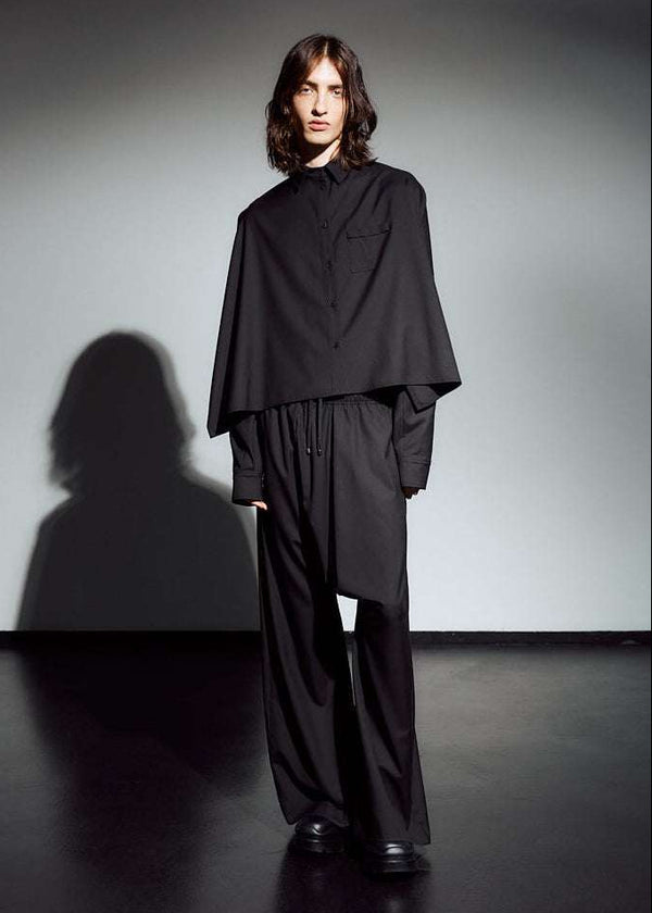 INTERNATIONAL CITIZEN.  Style: The Cubism Shirt is a 3-dimensional cube tilted on its axes to create a boxy minimal front body and dramatic drape in the back body and a utility pen pocket on the chest. Unisex Item. Front full body view. Made of Italian RWS Wool, Obsidian Black. Spiritually Infused, Sustainable Luxury Fashion in Berlin.