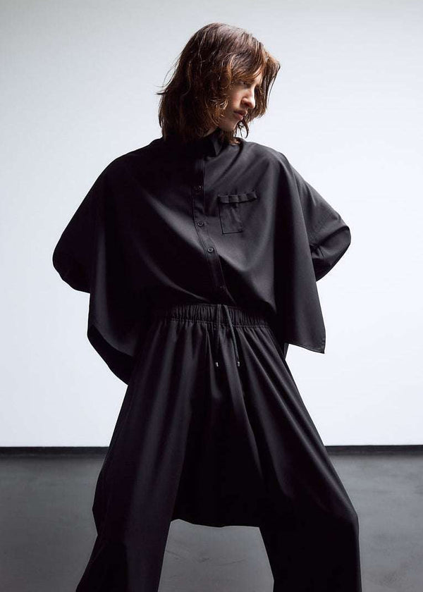 INTERNATIONAL CITIZEN.  Style: The Cubism Shirt is a 3-dimensional cube tilted on its axes to create a boxy minimal front body and a utility pen pocket on the chest. Unisex Item. Cropped front view. Made of Italian RWS Wool, Obsidian Black. Spiritually Infused, Sustainable Luxury Fashion in Berlin.
