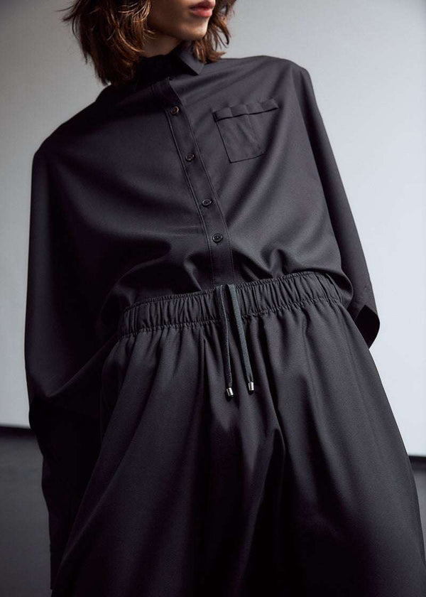 INTERNATIONAL CITIZEN.  Style: The Cubism Shirt is a 3-dimensional cube tilted on its axes to create a boxy minimal front body and a utility pen pocket on the chest. Unisex Item. Close up front photo on male model. Made of Italian RWS Wool, Obsidian Black. Spiritually Infused, Sustainable Luxury Fashion in Berlin.