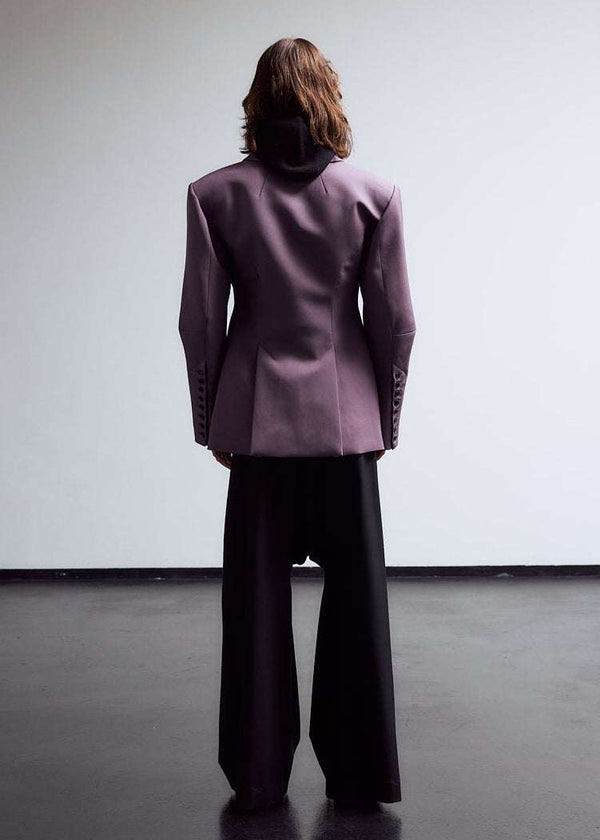 INTERNATIONAL CITIZEN.  Style: The Hourglass Jacket is named after its perfected silhouette, shaped with a nipped waist. Full body back photo of male model. Unisex Item. Made of Italian Wool, certified RWS, Amethyst Purple. Spiritually Infused, Sustainable Luxury Fashion in Berlin.