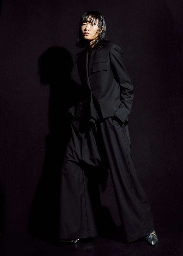 INTERNATIONAL CITIZEN.  Style: The Ascension Jacket. Front full body photo. Style has a tailored structured front body, bias under sleeves for a slim fit, and an asymmetrical collar and lapel. The jacket is made of Italian RWS Wool in Obsidian Black. Spiritually Infused, Sustainable Luxury Fashion in Berlin.