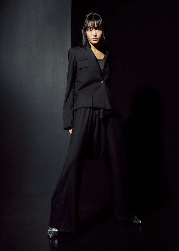 INTERNATIONAL CITIZEN.  Style: The Ascension Jacket. Front photo. Style has a tailored structured front body, and an asymmetrical collar and lapel. Lastly it has a handkerchief detail at the front button closure. The jacket is made of Italian RWS Wool in Obsidian Black. Spiritually Infused, Sustainable Luxury Fashion in Berlin.