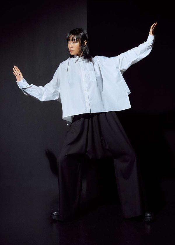 INTERNATIONAL CITIZEN.  Style: The Cubism Shirt is a 3-dimensional cube tilted on its axes to create a boxy minimal front body and dramatic drape in the back body. Unisex Item. Action photo. Made of Italian Organic Cotton, White Quartz. Spiritually Infused, Sustainable Luxury Fashion in Berlin.
