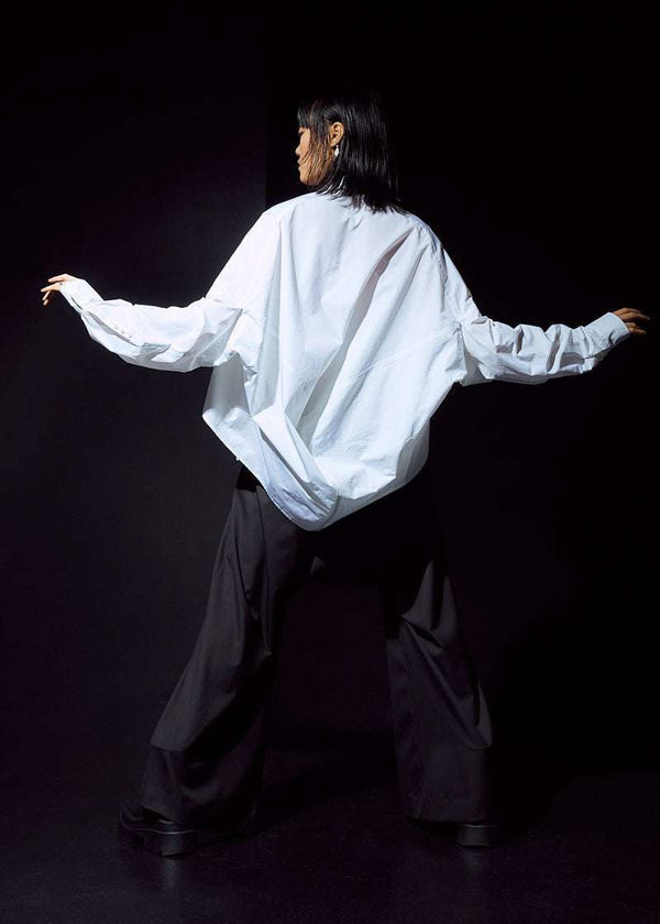 INTERNATIONAL CITIZEN.  Style: The Cubism Shirt is a 3-dimensional cube tilted on its axes to create a dramatic drape in the back body. Unisex Item. Full body back view. Made of Italian Organic Cotton, White Quartz. Spiritually Infused, Sustainable Luxury Fashion in Berlin.