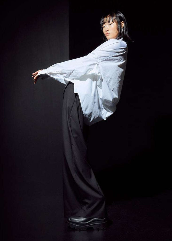 INTERNATIONAL CITIZEN.  Style: The Cubism Shirt is a 3-dimensional cube tilted on its axes to create a boxy minimal front body and dramatic drape in the back body. Unisex Item. Full body side view. Made of Italian Organic Cotton, White Quartz. Spiritually Infused, Sustainable Luxury Fashion in Berlin.