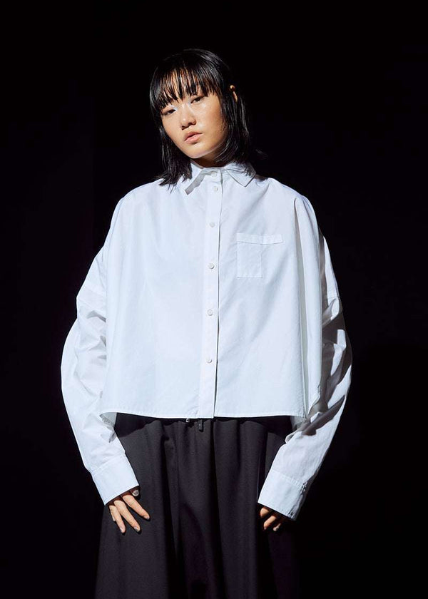 INTERNATIONAL CITIZEN.  Style: The Cubism Shirt is a 3-dimensional cube tilted on its axes to create a boxy minimal front body and a utility pen pocket on the chest. Unisex Item. Front photo. Made of Italian Organic Cotton, White Quartz. Spiritually Infused, Sustainable Luxury Fashion in Berlin.