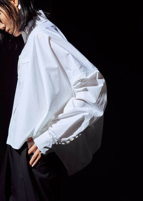 INTERNATIONAL CITIZEN.  Style: The Cubism Shirt is a 3-dimensional cube tilted on its axes to create a boxy minimal front body and dramatic drape in the back body. Unisex Item. Left side view. Made of Italian Organic Cotton, White Quartz. Spiritually Infused, Sustainable Luxury Fashion in Berlin.