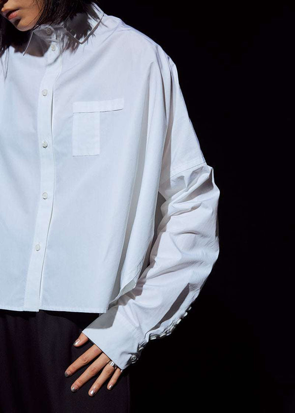 INTERNATIONAL CITIZEN.  Style: The Cubism Shirt is a 3-dimensional cube tilted on its axes to create a boxy minimal front body and a utility pen pocket on the chest. Unisex Item. Close up front right side photo. Made of Italian Organic Cotton, White Quartz. Spiritually Infused, Sustainable Luxury Fashion in Berlin.