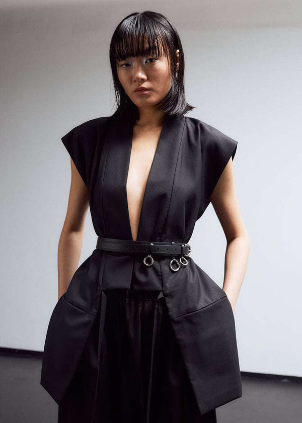 INTERNATIONAL CITIZEN.  Style: The Kimono Vest has a longer front body with inseam pockets and short back body. There are front ties and inseam belt slits for multiple ways to belt it. Unisex Item. Female front belted. Made of Italian Wool, certified (RWS) Responsible Wool Standard, Obsidian Black. Spiritually Infused, Sustainable Luxury Fashion in Berlin.