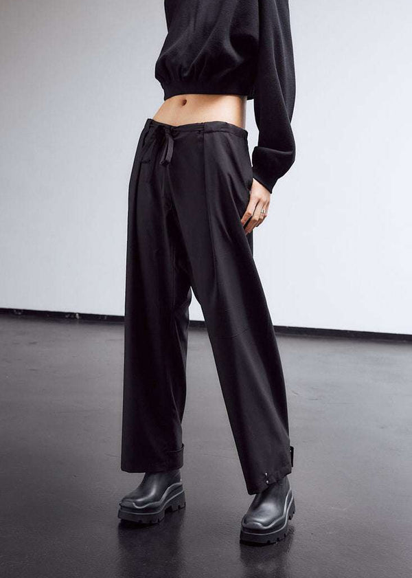INTERNATIONAL CITIZEN.  Style: The JiuJitsu Pants are have a drawstring closer at the waist,  a straight leg with silver snap hem straps and a thigh patch. Unisex item. Front photo. Made of Italian Wool, certified (RWS) Responsible Wool Standard, Obsidian Black. Spiritually Infused, Sustainable Luxury Fashion in Berlin.