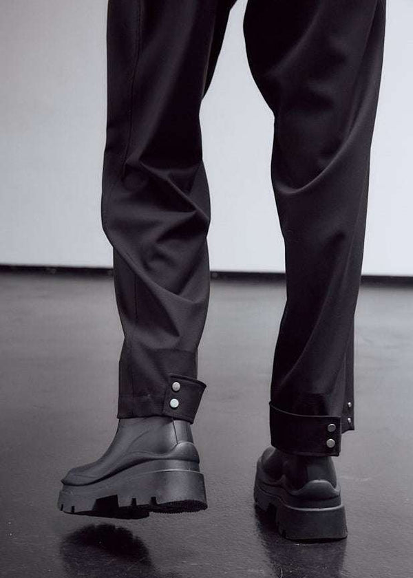 INTERNATIONAL CITIZEN.  Style: The JiuJitsu Pants feature a straight leg with silver snap hem straps and a thigh patch. Unisex item. Close up leg photo. Made of Italian Wool, certified (RWS) Responsible Wool Standard, Obsidian Black. Spiritually Infused, Sustainable Luxury Fashion in Berlin.