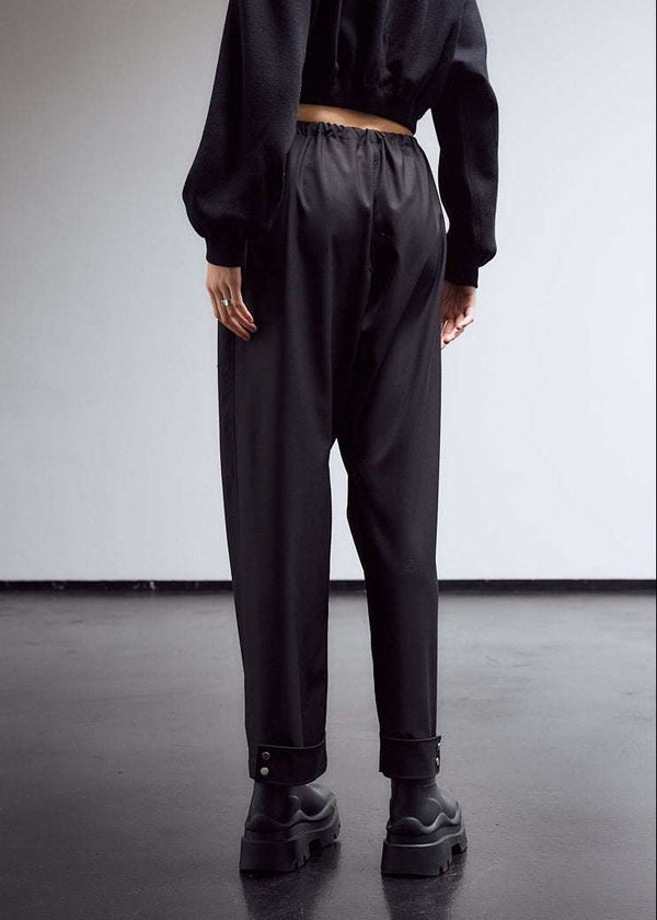 INTERNATIONAL CITIZEN.  Style: The JiuJitsu Pants are have a drawstring closer at the waist, and a straight leg with silver snap hem straps. Unisex item. Back photo. Made of Italian Wool, certified (RWS) Responsible Wool Standard, Obsidian Black. Spiritually Infused, Sustainable Luxury Fashion in Berlin.
