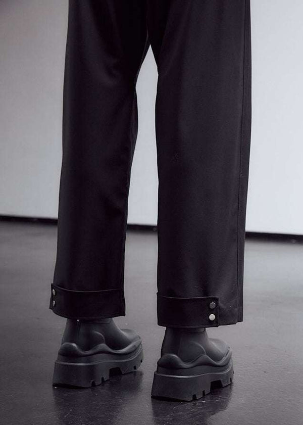 INTERNATIONAL CITIZEN.  Style: The JiuJitsu Pants feature a silver snap hem straps and a thigh patch. Unisex item. Close up back leg photo. Made of Italian Wool, certified (RWS) Responsible Wool Standard, Obsidian Black. Spiritually Infused, Sustainable Luxury Fashion in Berlin.
