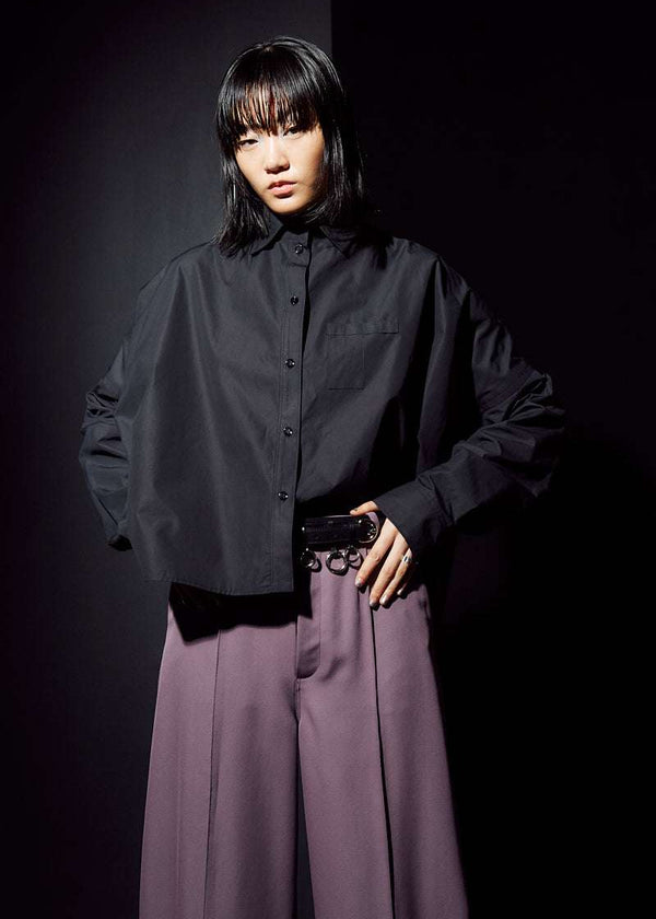 INTERNATIONAL CITIZEN.  Style: The Cubism Shirt is a 3-dimensional cube tilted on its axes to create a boxy minimal front body and dramatic drape in the back body and a utility pen pocket on the chest. Unisex Item. Front photo. Made of Italian Organic Cotton, Obsidian Black. Spiritually Infused, Sustainable Luxury Fashion in Berlin.