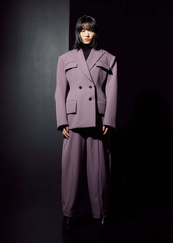 INTERNATIONAL CITIZEN.  Style: The Hourglass Jacket is named after its perfected silhouette, shaped with a nipped waist. It is double breasted with a 3-button closures, felt under collar and classic men’s tailoring techniques within the structure of the body. Front full body view. Unisex Item. Made of Italian Wool, certified RWS, Amethyst Purple. Spiritually Infused, Sustainable Luxury Fashion in Berlin.