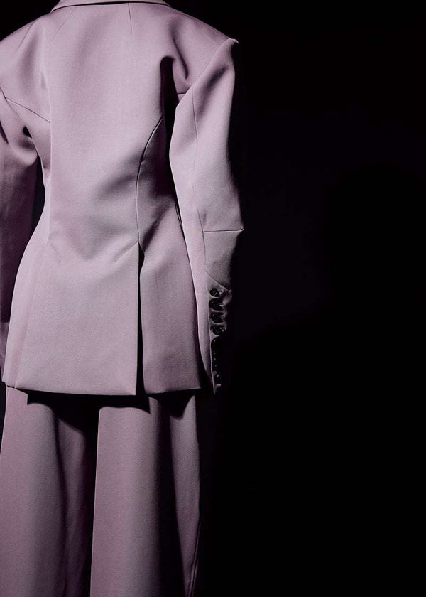 INTERNATIONAL CITIZEN.  Style: The Hourglass Jacket is named after its perfected silhouette, shaped with a nipped waist. It has the brand iconic 8-button sleeve vent closure and oversized bent sleeve. Unisex Item. Close up back view. Made of Italian Wool, certified RWS, Amethyst Purple. Spiritually Infused, Sustainable Luxury Fashion in Berlin.