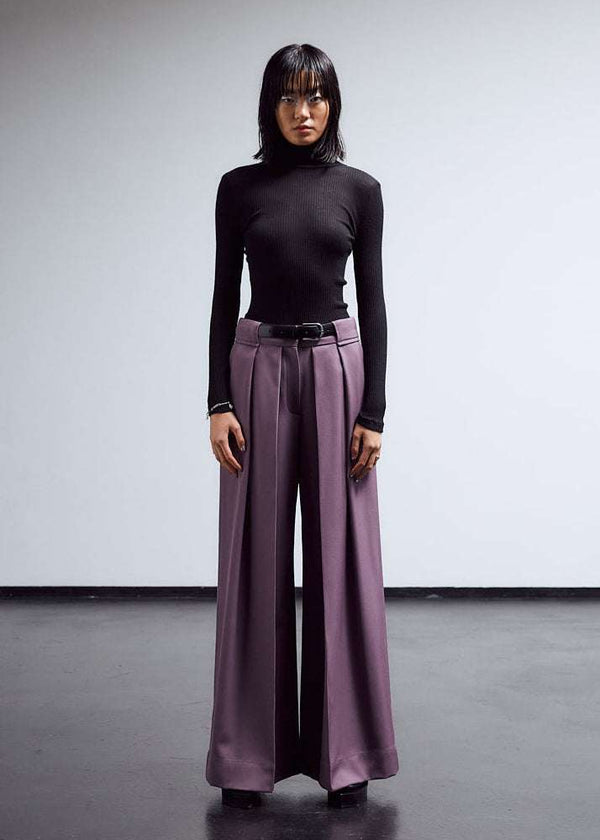 INTERNATIONAL CITIZEN.  Style: The Deep Pleated Pant, falls below the natural waist. The pleats nearly meet at the center front. Made of Italian RWS Wool, Amethyst Purple. Full body front view. Spiritually Infused, Sustainable Luxury Fashion in Berlin.