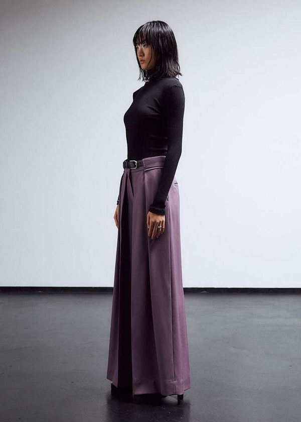 INTERNATIONAL CITIZEN.  Style: The Deep Pleated Pant, falls below the natural waist. Made of Italian RWS Wool, Amethyst Purple. Side front view. Spiritually Infused, Sustainable Luxury Fashion in Berlin.