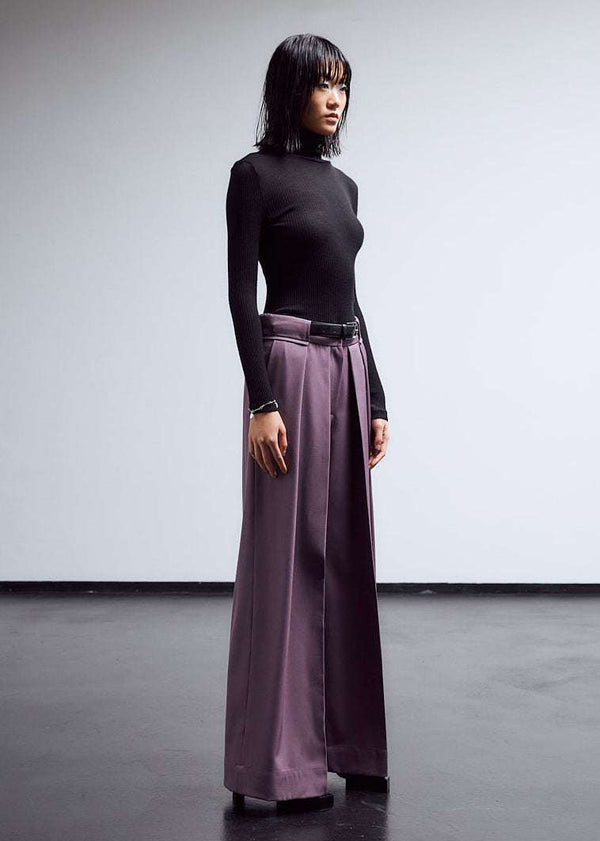 INTERNATIONAL CITIZEN.  Style: The Deep Pleated Pant, falls below the natural waist. Made of Italian RWS Wool, Amethyst Purple. Right side front view. Spiritually Infused, Sustainable Luxury Fashion in Berlin.