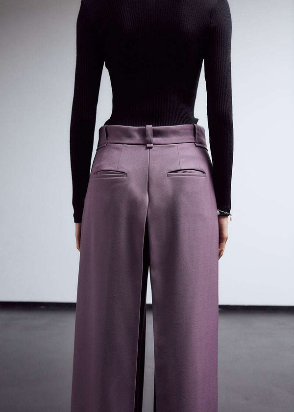 INTERNATIONAL CITIZEN.  Style: The Deep Pleated Pant, falls below the natural waist. The pleats nearly meet at the ccenter back. Made of Italian RWS Wool, Amethyst Purple. Close up back view. Spiritually Infused, Sustainable Luxury Fashion in Berlin.