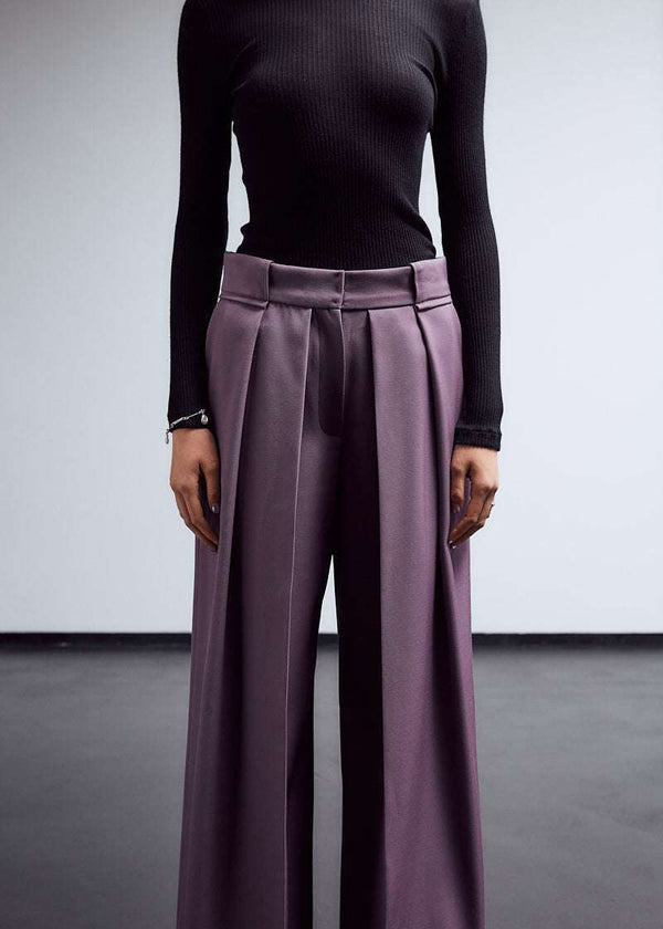 INTERNATIONAL CITIZEN.  Style: The Deep Pleated Pant, falls below the natural waist. The pleats nearly meet at the center front. Made of Italian RWS Wool, Amethyst Purple. Close up front view without a belt. Spiritually Infused, Sustainable Luxury Fashion in Berlin.