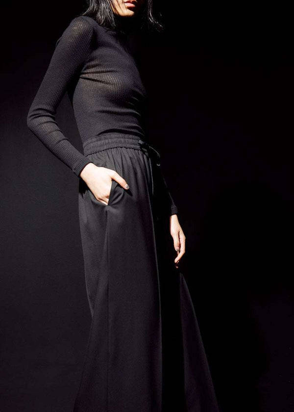 INTERNATIONAL CITIZEN.  Style: The Arcana Pant. Close up side view. Style has a relaxed fit with front pin-tucks and in seam pockets. Unisex Item. The pants are made of Italian RWS Wool in Obsidian Black. Spiritually Infused, Sustainable Luxury Fashion in Berlin.