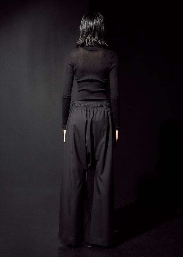 INTERNATIONAL CITIZEN.  Style: The Lanna Pant have a dropped crotch with excessive volume eased into an elastic waistband. Unisex Item. Back photo. Made of Italian Wool, certified (RWS) Responsible Wool Standard, Obsidian Black. Spiritually Infused, Sustainable Luxury Fashion in Berlin.

