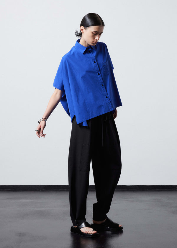 INTERNATIONAL CITIZEN.  Style: The Cubism Shirt is a 3-dimensional cube tilted on its axes to create a boxy minimal front body. Unisex Item. Side front full view. Made of Italian Organic Cotton, Lapis Lazuli Blue. Spiritually Infused, Sustainable Luxury Fashion in Berlin.