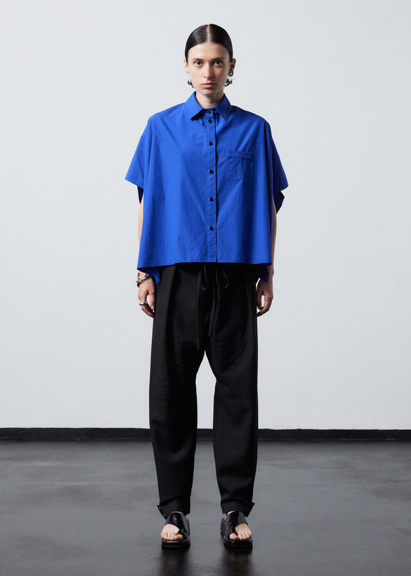 INTERNATIONAL CITIZEN.  Style: The Cubism Shirt is a 3-dimensional cube tilted on its axes to create a boxy minimal front body  and a utility pen pocket on the chest. Unisex Item. Front full body view. Made of Italian Organic Cotton, Lapis Lazuli Blue. Spiritually Infused, Sustainable Luxury Fashion in Berlin.