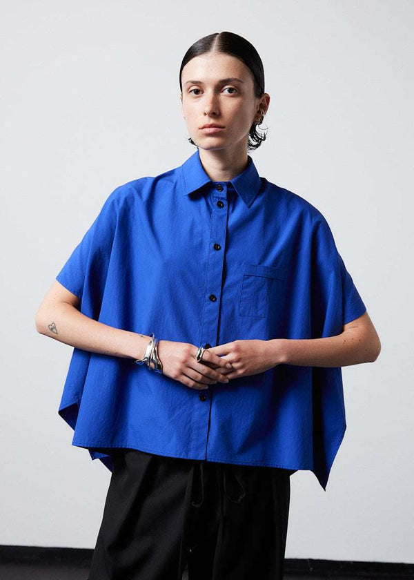 INTERNATIONAL CITIZEN.  Style: The Cubism Shirt is a 3-dimensional cube tilted on its axes to create a boxy minimal front body and a utility pen pocket on the chest. Unisex Item. Close up front photo. Made of Italian Organic Cotton, Lapis Lazuli Blue. Spiritually Infused, Sustainable Luxury Fashion in Berlin.