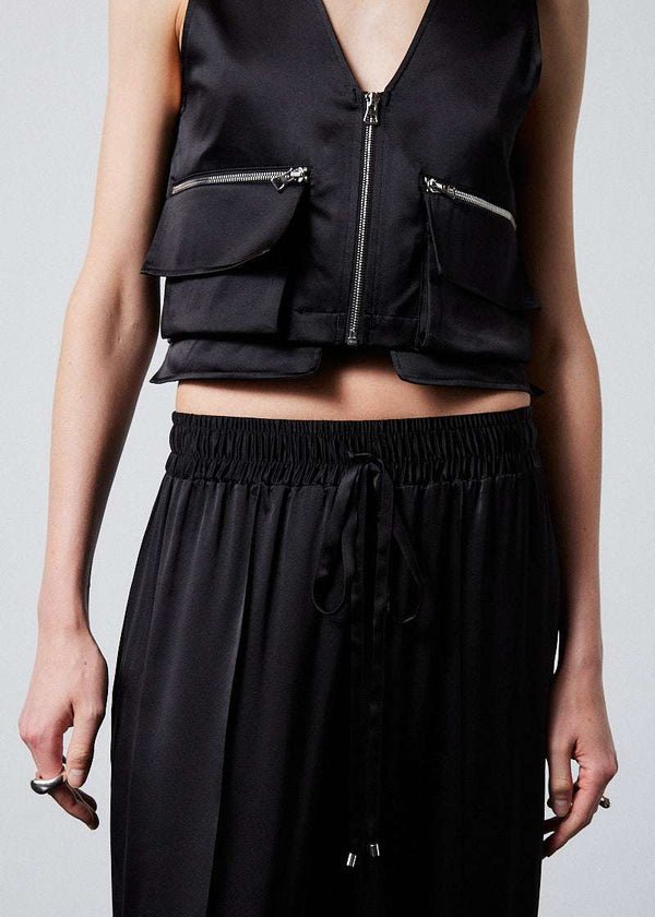 INTERNATIONAL CITIZEN.  Style: The Arcana Pant. Close up front view. Style has a relaxed fit with front pin-tucks and excessive volume eased into the waistband. Unisex Item. The pants are made of Italian organic silk in Obsidian Black. Spiritually Infused, Sustainable Luxury Fashion in Berlin.