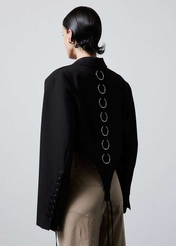 INTERNATIONAL CITIZEN.  Style: The French-Cut Jacket is oversized in the fit with a high french-cut hemline. Side back photo. Unisex item. Made of Italian Wool, Obsidian Black. Spiritually Infused, Sustainable Luxury Fashion in Berlin.