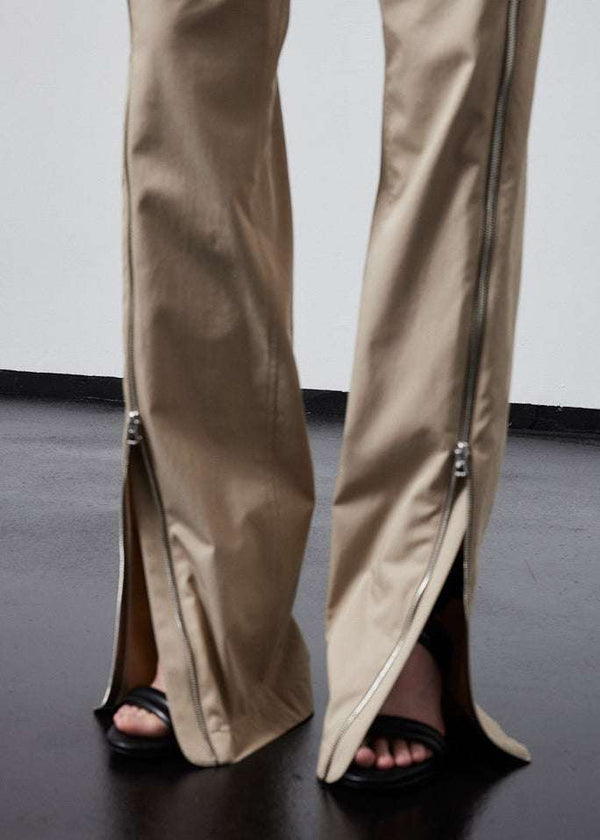 INTERNATIONAL CITIZEN.  Style: The Racer Pants have zippers down the entire front legs from the waistband to the hemline and a fly front zip. Made of Italian Organic Cotton Twill, Dune. Spiritually Infused, Sustainable Luxury Fashion in Berlin. Close up leg hem photo.