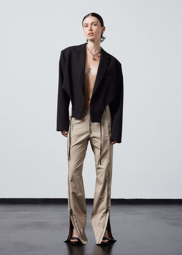 INTERNATIONAL CITIZEN.  Style: The Racer Pants have zippers down the entire front legs from the waistband to the hemline and a fly front zip. Made of Italian Organic Cotton Twill, Dune. Spiritually Infused, Sustainable Luxury Fashion in Berlin. Full front view.
