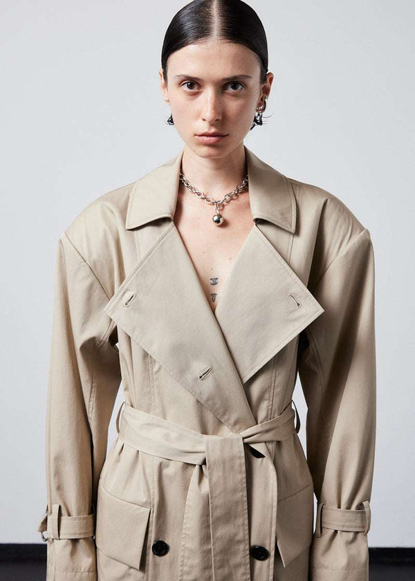 INTERNATIONAL CITIZEN.  Style: The Eclipse Jacket. A unisex, asymmetrical along the hemline and oversized with soft shoulder pads for collapsed structure. It is double breasted and made of Italian Organic Cotton, Dune. Close up front view. Spiritually Infused, Sustainable Luxury Fashion in Berlin.