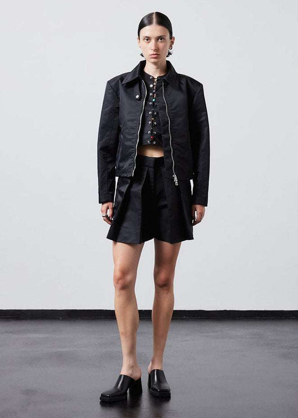 INTERNATIONAL CITIZEN.  Style: Ajna Jacket. A black boxy jacket with sporty tailoring, featuring square shoulders, tapered sleeves, and zipper closures. The jacket is made from of Italian water repellent, post-consumer recycled Nylon Gaberdine. Full body view worn open. Spiritually Infused, Sustainable Luxury Fashion in Berlin.