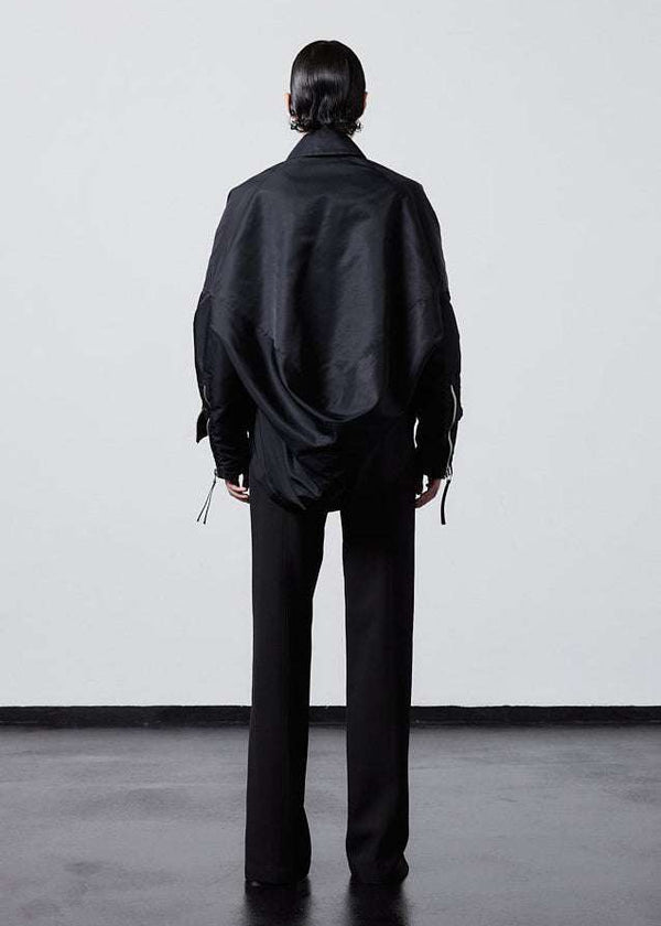 INTERNATIONAL CITIZEN.  Style: The Cube Coat, is a 3D cube tilted on its axes to create a boxy minimal front body and dramatic drape in the back body. Full body back view. Unisex style. Made of Italian post-consumer recycled Nylon, Obsidian Black. Spiritually Infused, Sustainable Luxury Fashion in Berlin.