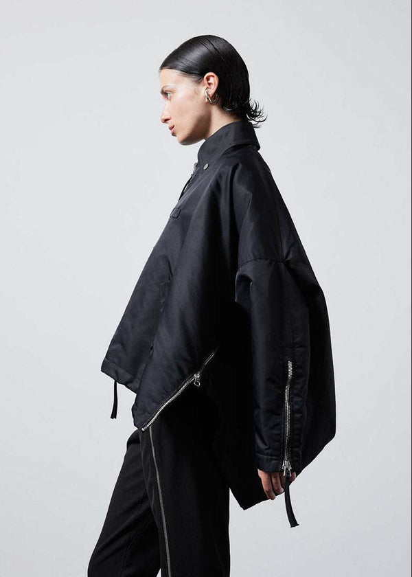INTERNATIONAL CITIZEN.  Style: The Cube Coat, is a 3D cube tilted on its axes to create a boxy minimal front body and dramatic drape in the back body. Unisex style. Side profile view. Made of Italian post-consumer recycled Nylon, Obsidian Black. Spiritually Infused, Sustainable Luxury Fashion in Berlin.